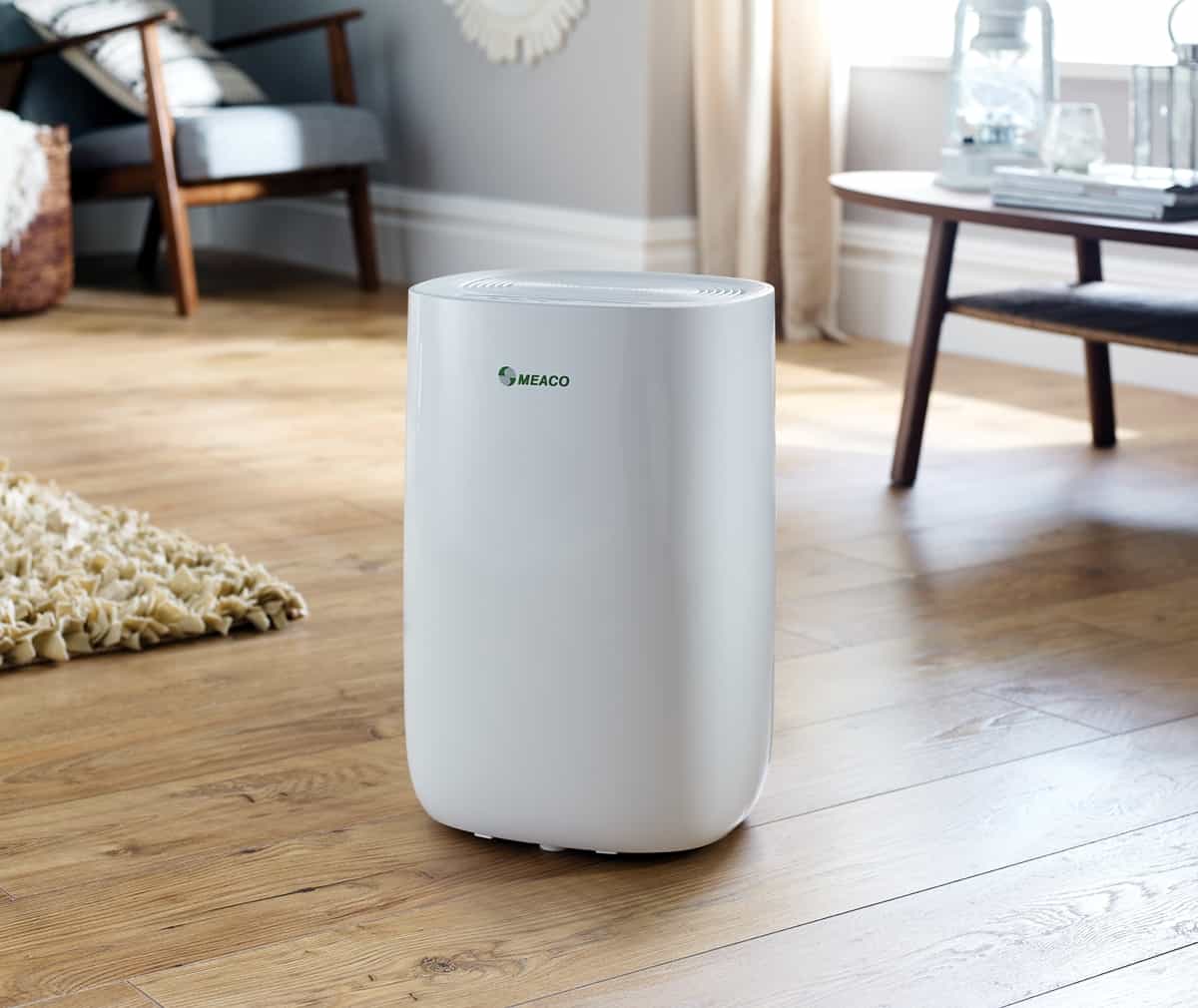 ABC range dehumidifier in the middle of a room with wooden floor, an arm chair and rug