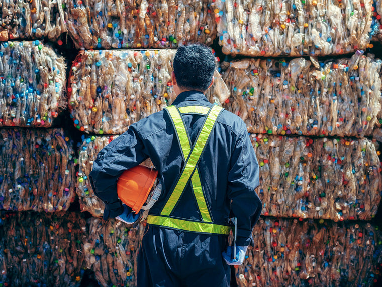 Plastic and cardboard recycling plant with man with high vis surveying