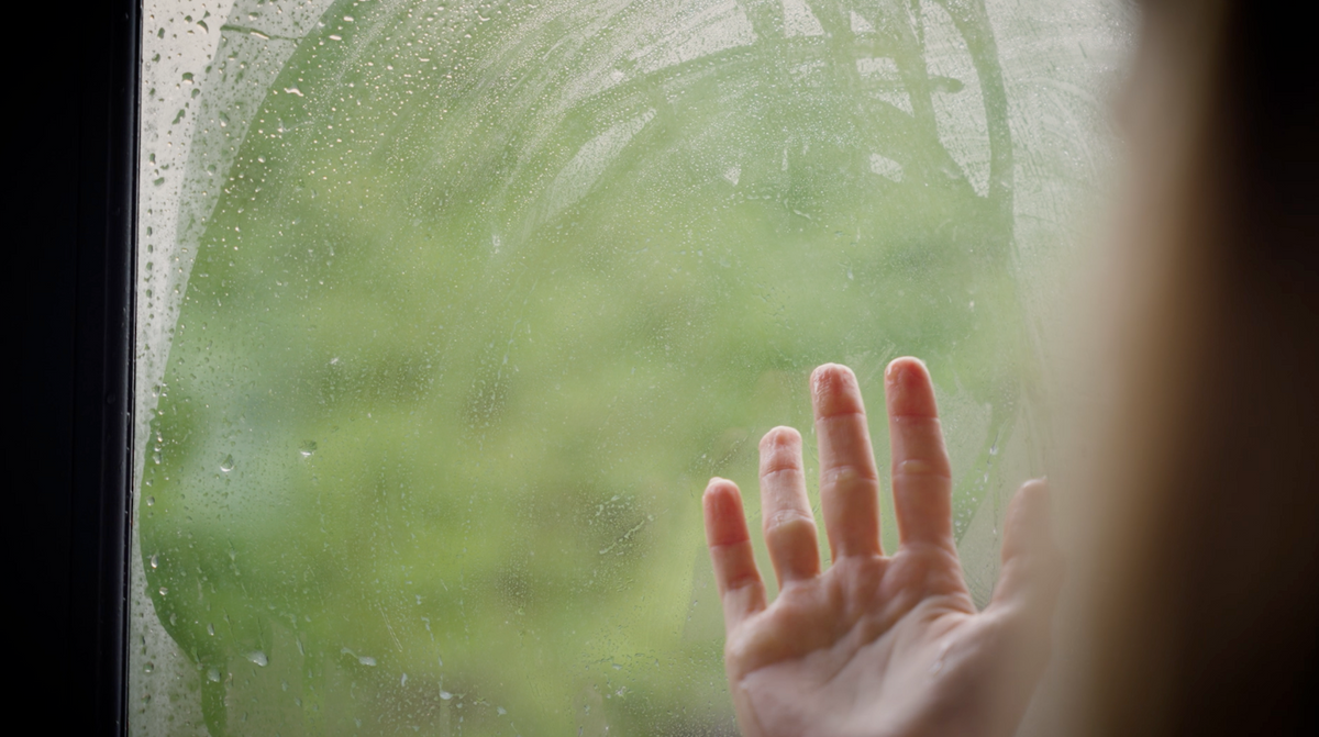 Hand wiping condensation off window