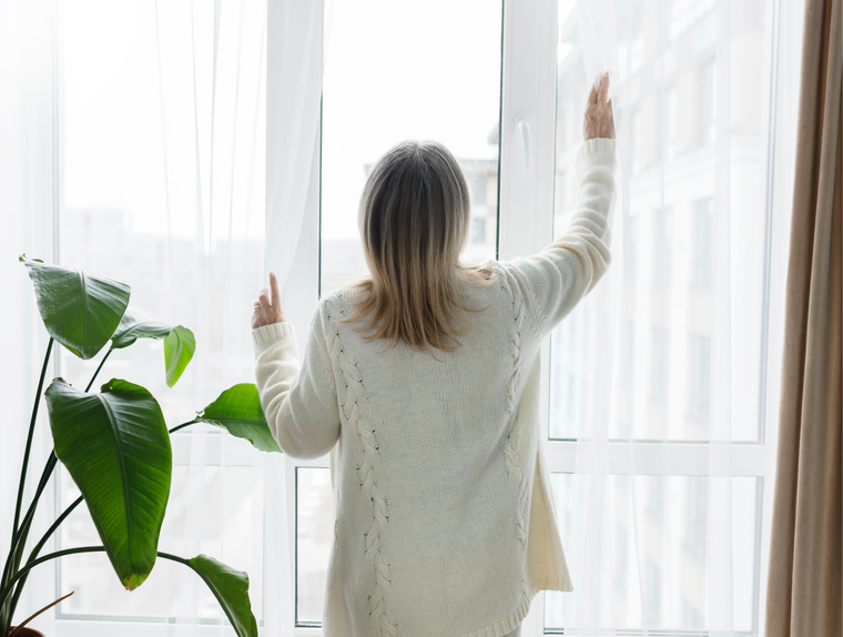 Woman opening window to help ventilate and manage humidity